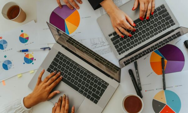 Persons Using Laptops on Table with Charts