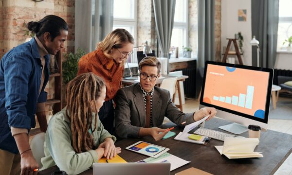 A Group of People Discussing Beside a Desktop